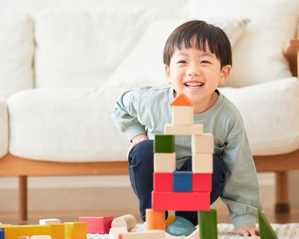 Generatorkinderen hebben veel energie maar hebben ook begeleiding nodig Een erg blij kind dat opgewonden lacht nadat het een spel heeft voltooid waarbij het kleine speelblokken op elkaar stapelde om een structuur te bouwen